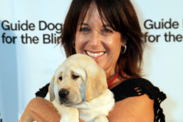 Debi Morgan holding a yellow Lab puppy.