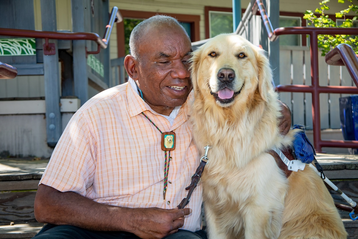 Tony sits with his arm around his Golden Retriever guide dog, Jagger
