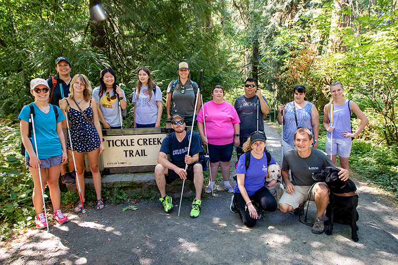 A group photo of campers at Camp GDB at the trailhead of a hiking path.