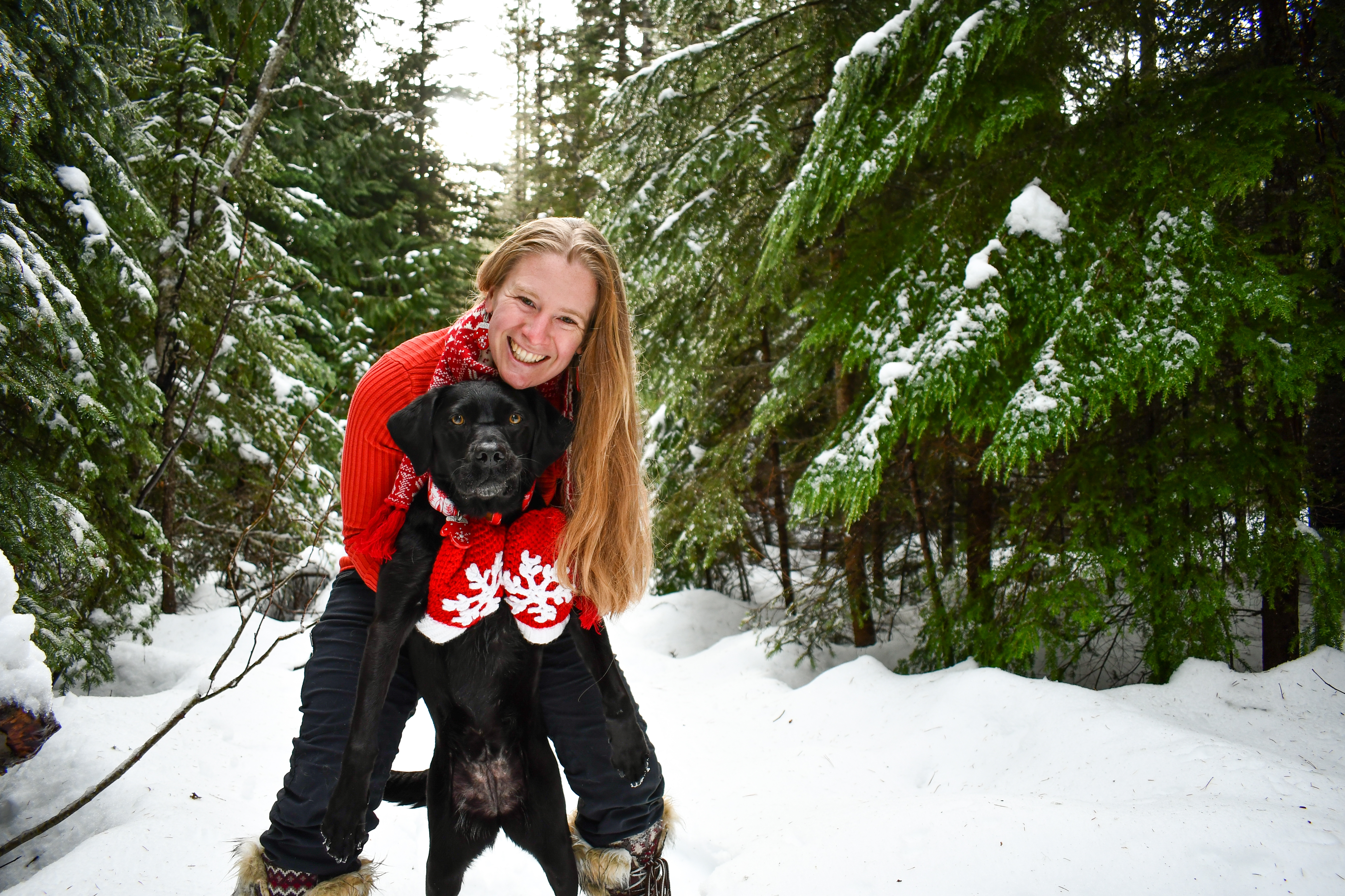 Jamie Mattison with a black Lab on a snowy forested path.