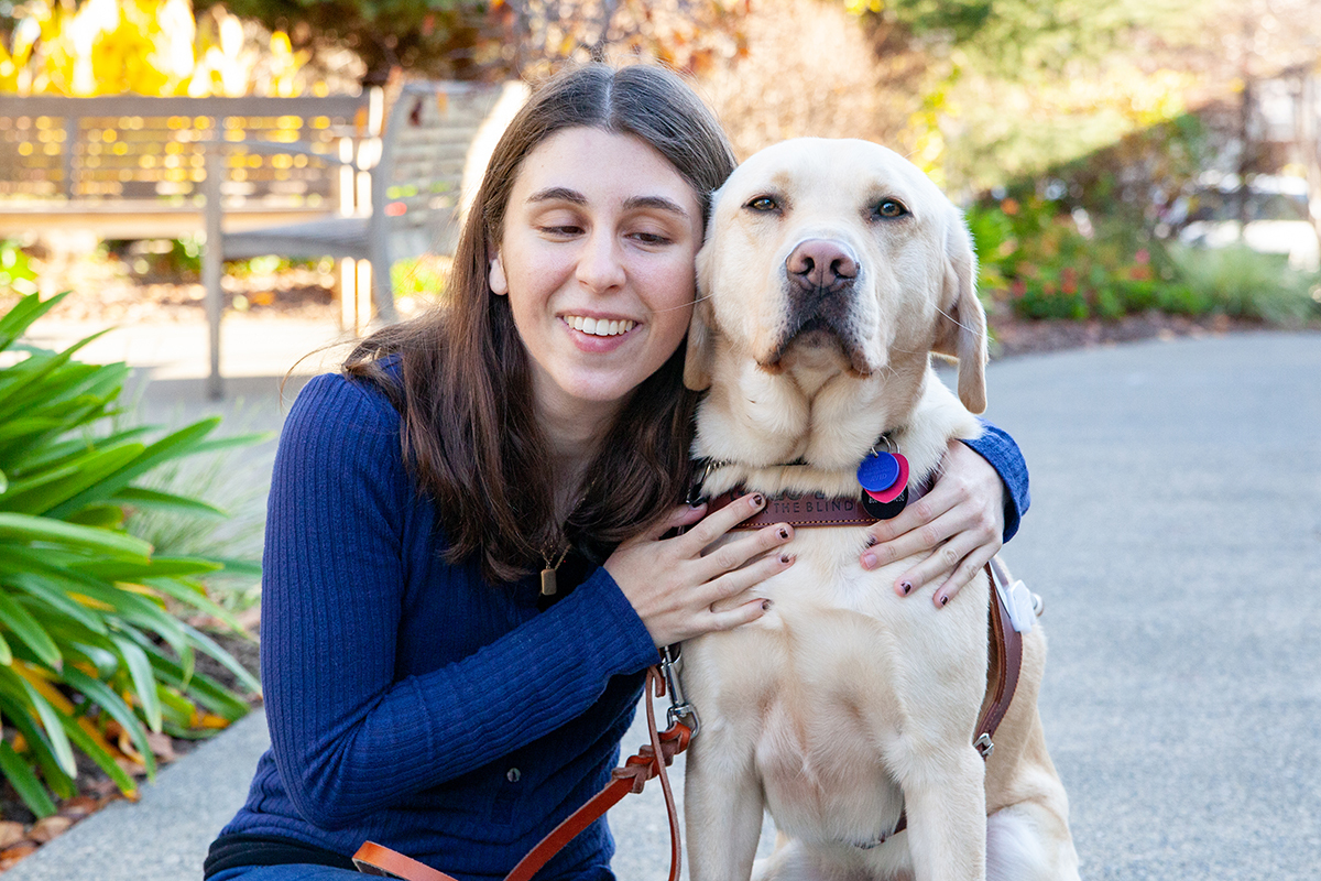 A woman hugs a yellow Lab guide dog