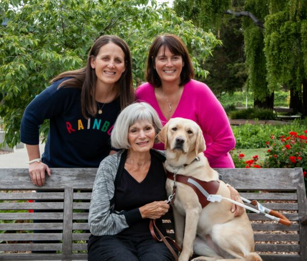 Three women and a yellow Lab guide dog.