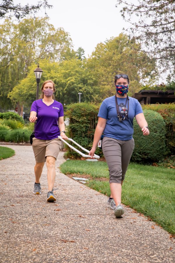 Two members of the GDB Training staff demonstrate how they are able to use extended training tools during training in order to maintain required social distancing.