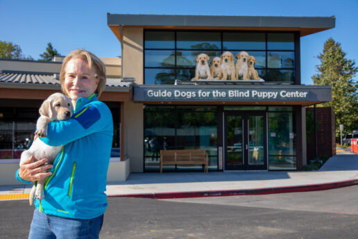 GDB CEO Christine Benninger snuggles a yellow Lab puppy in front of the Puppy Center.