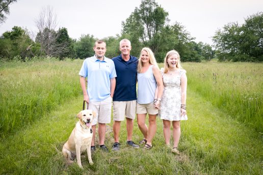 Family photo of the Edwards family including GDB clients Ethan and Elyssa. Ethan's yellow Lab guide dog, Ginsburg, stands by his side.