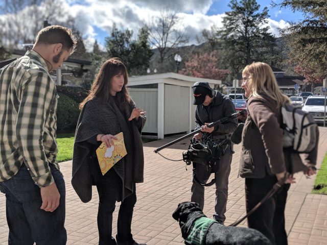 Dana works with her crew during the filming of Pick of the Litter. She gives instructions to a puppy raiser who is working with a black Lab guide dog in training.